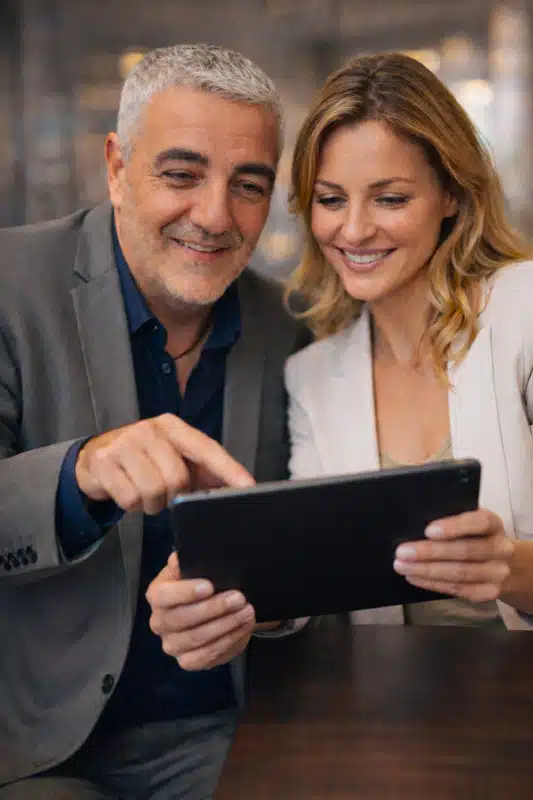 Serge Latour en consultation avec une cliente, analysant la visibilité d'un site web sur tablette. Focus sur la qualité de l'image de marque et le positionnement Google.